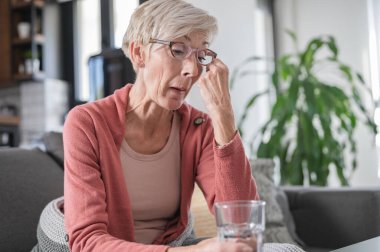 Yaşlı yaşlı kadın günlük ilaçlarını alıyor. Hap almaya hazırlanıyorum.