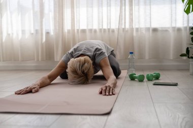 İçeride yoga yapan aktif son sınıf öğrencisi bir kadın.