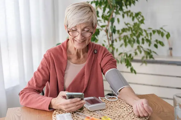 Seniorin Sitzt Allein Hause Und Misst Ihren Blutdruck Mit Einem — Stockfoto