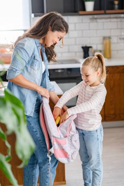 Anne ve kızı öğle yemeğini okul çantasına koyuyorlar.