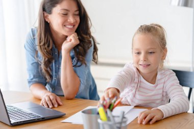 Mutlu anne ve kız evde birlikte okuyorlar, online eğitim alıyorlar.
