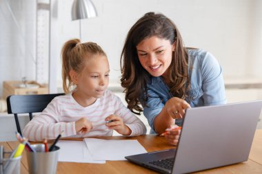 Mutlu anne ve kız evde birlikte okuyorlar, online eğitim alıyorlar.