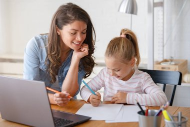 Mutlu anne ve kız evde birlikte okuyorlar, online eğitim alıyorlar.