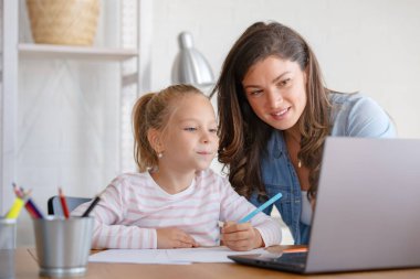 Mutlu anne ve kız evde birlikte okuyorlar, online eğitim alıyorlar.