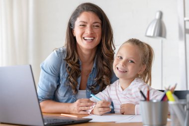 Mutlu anne ve kız evde birlikte okuyorlar, online eğitim alıyorlar.