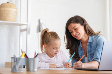 Mutlu anne ve kız evde birlikte okuyorlar, online eğitim alıyorlar.