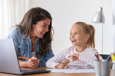 Mutlu anne ve kız evde birlikte okuyorlar, online eğitim alıyorlar.