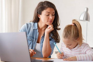 Mutlu anne ve kız evde birlikte okuyorlar, online eğitim alıyorlar.