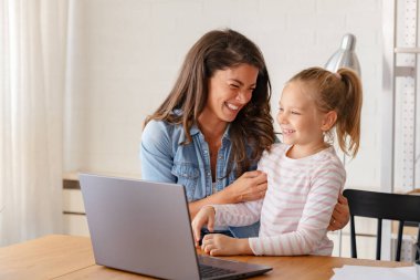 Mutlu anne ve kız evde birlikte okuyorlar, online eğitim alıyorlar.