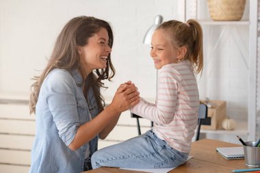 Neşeli ve sevecen bir an, neşeli bir anne ve kızının sıcak gülümsemelerini, kucaklaşmalarını ve birlikte eğlenmelerini gözler önüne seriyor..