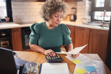 Mutfakta dizüstü bilgisayar kullanan son sınıf kadın serbest yazar.  