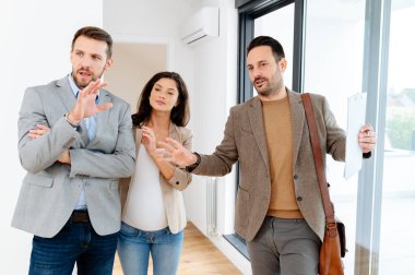 Adam ve hamile karısı, bir emlakçıyla konuşuyorlar. Satılık ya da kiralık bir daireyi ziyaret ediyorlar. Müstakbel ebeveynler daire alıyor. Emlak kavramı