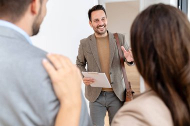 Adam ve hamile karısı, bir emlakçıyla konuşuyorlar. Satılık ya da kiralık bir daireyi ziyaret ediyorlar. Müstakbel ebeveynler daire alıyor. Emlak kavramı