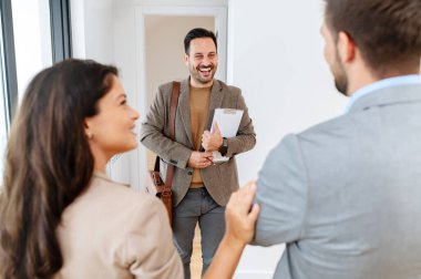 Adam ve hamile karısı, bir emlakçıyla konuşuyorlar. Satılık ya da kiralık bir daireyi ziyaret ediyorlar. Müstakbel ebeveynler daire alıyor. Emlak kavramı