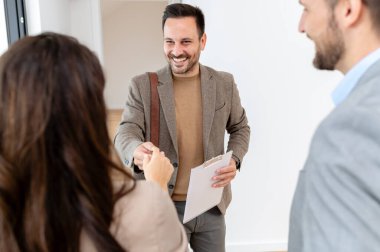 Adam ve hamile karısı, bir emlakçıyla konuşuyorlar. Satılık ya da kiralık bir daireyi ziyaret ediyorlar. Müstakbel ebeveynler daire alıyor. Emlak kavramı