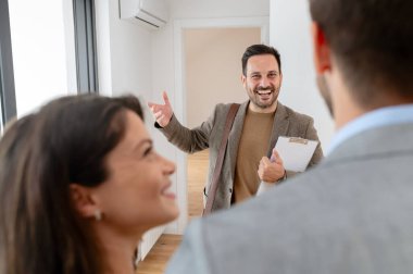 Adam ve hamile karısı, bir emlakçıyla konuşuyorlar. Satılık ya da kiralık bir daireyi ziyaret ediyorlar. Müstakbel ebeveynler daire alıyor. Emlak kavramı