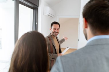 Adam ve hamile karısı, bir emlakçıyla konuşuyorlar. Satılık ya da kiralık bir daireyi ziyaret ediyorlar. Müstakbel ebeveynler daire alıyor. Emlak kavramı