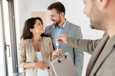 Adam ve hamile karısı, bir emlakçıyla konuşuyorlar. Satılık ya da kiralık bir daireyi ziyaret ediyorlar. Müstakbel ebeveynler daire alıyor. Emlak kavramı