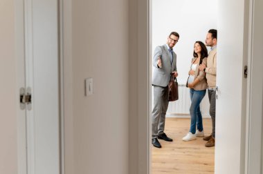 Adam ve hamile karısı, bir emlakçıyla konuşuyorlar. Satılık ya da kiralık bir daireyi ziyaret ediyorlar. Müstakbel ebeveynler daire alıyor. Emlak kavramı