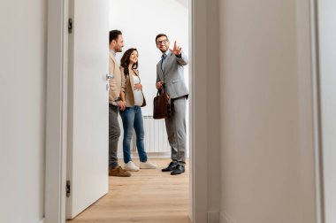 Adam ve hamile karısı, bir emlakçıyla konuşuyorlar. Satılık ya da kiralık bir daireyi ziyaret ediyorlar. Müstakbel ebeveynler daire alıyor. Emlak kavramı