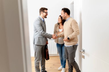 Adam ve hamile karısı, bir emlakçıyla konuşuyorlar. Satılık ya da kiralık bir daireyi ziyaret ediyorlar. Müstakbel ebeveynler daire alıyor. Emlak kavramı