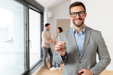 Adam ve hamile karısı, bir emlakçıyla konuşuyorlar. Satılık ya da kiralık bir daireyi ziyaret ediyorlar. Müstakbel ebeveynler daire alıyor. Emlak kavramı