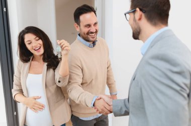 Adam ve hamile karısı, bir emlakçıyla konuşuyorlar. Satılık ya da kiralık bir daireyi ziyaret ediyorlar. Müstakbel ebeveynler daire alıyor. Emlak kavramı