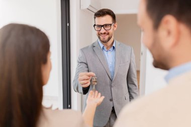 Adam ve hamile karısı, bir emlakçıyla konuşuyorlar. Satılık ya da kiralık bir daireyi ziyaret ediyorlar. Müstakbel ebeveynler daire alıyor. Emlak kavramı