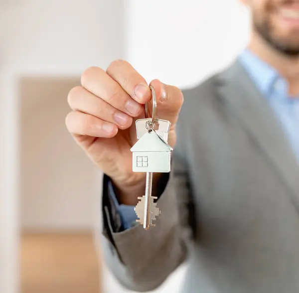 The real estate agent holds a key of a property. Buying an apartment. Real estate and mortgage concept.