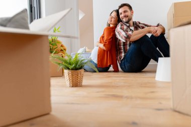 Karton kutularla yerde oturan çift yeni eve taşınıyor. 