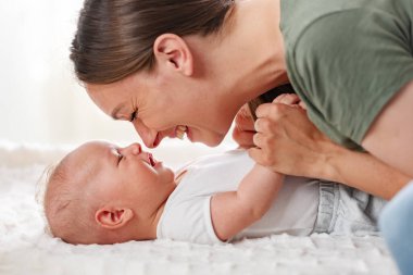 Anne evde yeni doğmuş bir bebekle oynuyor.
