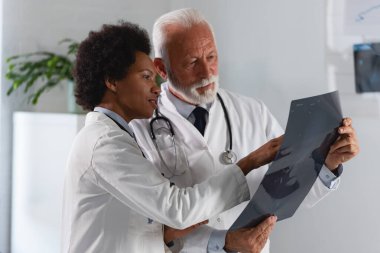 Erkek doktor hastanedeki meslektaşına röntgen sonuçlarını gösteriyor.