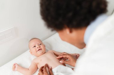 Çocuk doktoru küçük çocuğu hastanede muayene ediyor. Küçük oğlu olan bir çocuk doktoru.