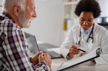 Doktor klinikteki kıdemli adamla konuşuyor.