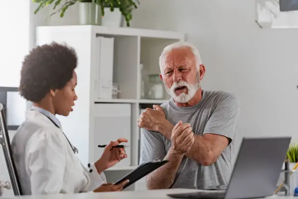 African American Woman Doctor Examining Senior Patient Stock Photo