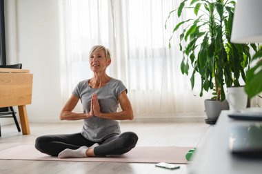 Yetişkin bir kadın oturma odasında meditasyon yapıyor. sağlıklı yaşam tarzı. 