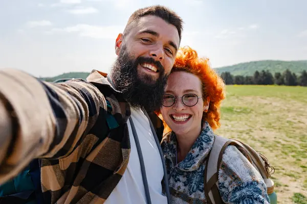 Mutlu çift çayırda selfie çekiyor.