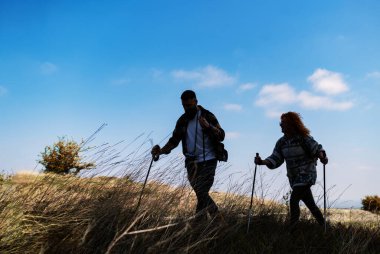 Sırt çantasına aşık genç bir çift çayırda yürüyor.