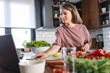 Mutfak masasında yemek hazırlayan gülümseyen kadın. Mutfakta salata yapan kadın..  