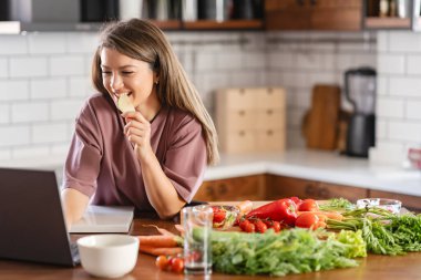 Evde dizüstü bilgisayar kullanan genç bir kadın. 