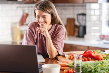 Evde dizüstü bilgisayar kullanan genç bir kadın. 