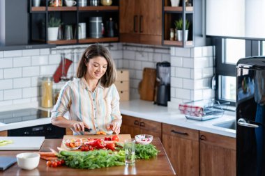 Kadın mutfakta salata pişiriyor. 