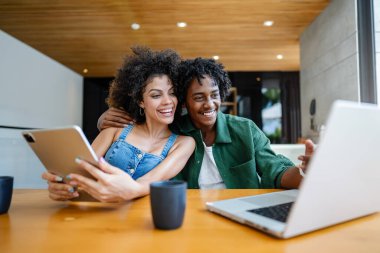 Mutlu Afro-Amerikan çift dizüstü bilgisayar ve tablet kullanıyor.