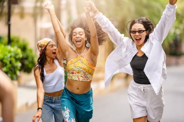 Bir grup mutlu genç arkadaş bir sokakta birlikte yürüyorlar..