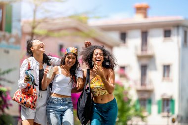 Bir grup mutlu genç arkadaş bir sokakta birlikte yürüyorlar..