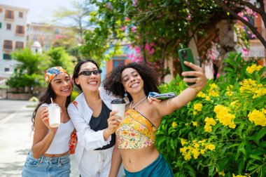 Yazın sokakta selfie çeken üç kadın arkadaş. 
