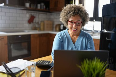 Evde dizüstü bilgisayar kullanan bir kadın. 