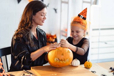 Mutlu anne ve kız evde Cadılar Bayramı feneri yapıyorlar.