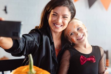 Mutlu anne ve kız Cadılar Bayramı partisinde selfie çekiyorlar.