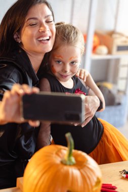 Mutlu anne ve kız Cadılar Bayramı partisinde selfie çekiyorlar.
